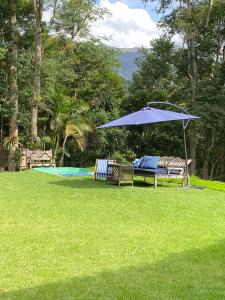 een blauwe parasol en twee stoelen in een tuin bij Chez nous in Petrópolis +69 foto's