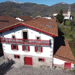 Edificio blanco con puertas rojas y balcón en Apartamentos en Baztan HIRU KABI, BIGA, 