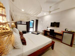 um quarto com uma cama, uma secretária e uma televisão em L'Hédone, hôtel de charme em Ouagadougou