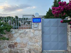 a blue garage door with a sign on a stone wall at Villa Maxima Lavrio in Thorikón