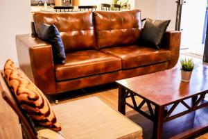 a brown leather couch in a living room with a table at Tanjung Jara Cottage - with indoor pool in Dungun