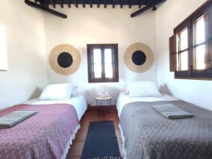 Dos camas en una habitación con dos ventanas. en Fery & Nico, en Granada