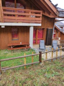 a wooden house with two chairs and a fence at Appartement valmeinier 6 personnes in Valmeinier