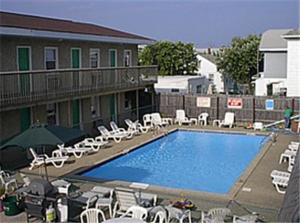a large swimming pool with chairs and a building at Offshore Motel in Seaside Heights