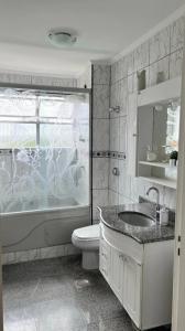 uma casa de banho com um WC, uma banheira e um lavatório. em Apartamento no topo da Ilha Porchat em São Vicente