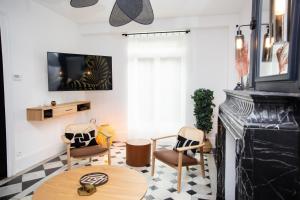 een woonkamer met een open haard, stoelen en een tafel bij Villa L'Anse - 1er étage in Étretat