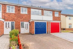 una casa de ladrillo con un garaje azul y rojo en Whetstone House en Ketteringham