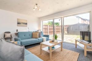 a living room with a blue couch and a tv at Whetstone House in Ketteringham