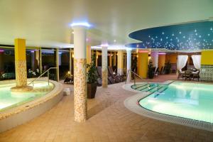 a hotel lobby with a pool and tables and chairs at Calimbra Wellness Hotel Superior in Miskolctapolca