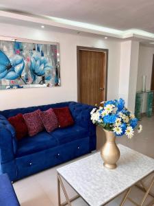 a blue couch in a living room with a vase with flowers at Hostal Sabanero in Barranquilla