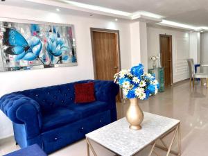 a blue couch in a living room with a vase of flowers at Hostal Sabanero in Barranquilla