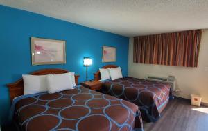 Habitación de hotel con 2 camas y paredes azules en American Inn Motel, en Pratt