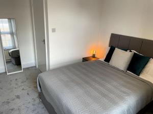 a bedroom with a large bed with a lamp on a table at Priestley Apartments Apt 1 in Nantwich