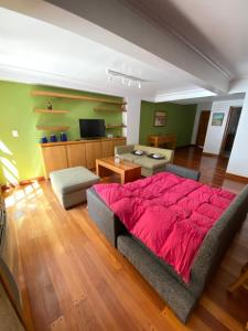 1 dormitorio con cama roja y sala de estar en Mza Holiday Home en Mendoza