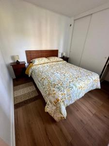 a bedroom with a bed with a floral comforter at Departamento Frente Hospital Chillan in Chillán