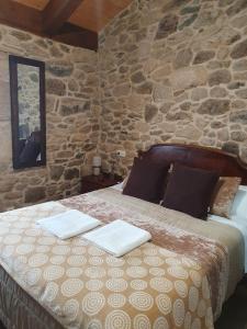 a bed in a room with a stone wall at La Pallota de San Cristobal in Palas de Rei 