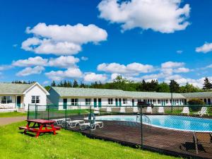 a swimming pool with a picnic table next to a building at Anne Shirley Motel & Cottages in Cavendish