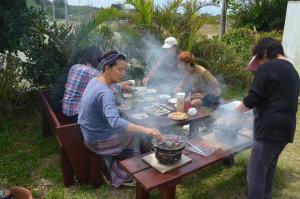 a group of people standing around a table preparing food at Guest House Isa in Motobu