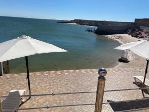 a beach with two umbrellas and chairs and the ocean at Hébergement dakhla plaisance in Dakhla