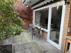 d'une terrasse avec une table et des chaises à côté d'une fenêtre. dans l'établissement Ferienwohnung Mühlenwarf, à Emden