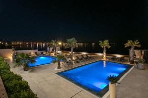een zwembad met palmbomen op een patio 's nachts bij Malibu Imperial Resort in Vir