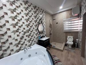 a bathroom with a tub and a toilet at T-Roys Apartments in Accra