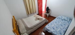 a small room with two beds and a chair at Casa Caiçara Centro in Paraty