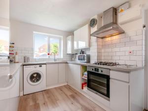 a white kitchen with a washer and dryer in it at Turnstone House in Birchington