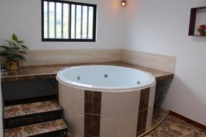 Hotel Paucura في Pácora: حوض استحمام كبير في حمام مع نافذة