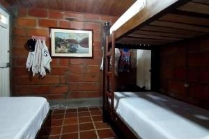een slaapkamer met 2 stapelbedden en een bakstenen muur bij Acogedora casa de campo en el oriente de Antioquia in El Retiro