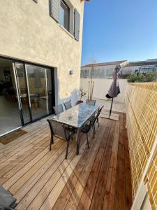 een patio met een tafel en stoelen op een houten terras bij Villa 8 personnes bord de mer climatisée in Saintes-Maries-de-la-Mer