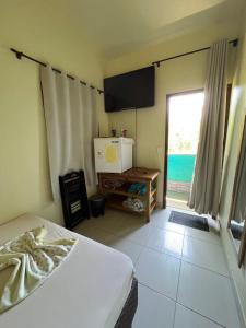 a bedroom with a bed and a television and a window at Pousada Casarão in Imbituba