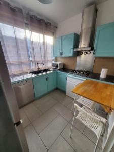 a kitchen with blue cabinets and a wooden table at Apartment 2 or 3 bedrooms near Paris in Suresnes