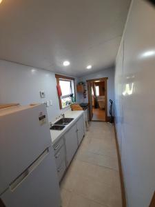 uma cozinha com um frigorífico branco e um lavatório em The Capitain's Cabin em Bluff