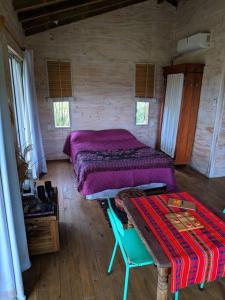 Un dormitorio con una cama y una mesa. en Hermosa cabaña en la naturaleza. Chacra La Fiaca, en Colonia del Sacramento