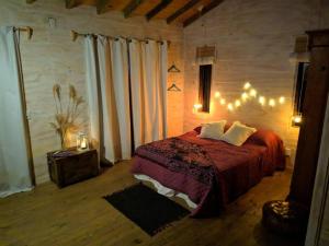1 dormitorio con cama con manta roja y luces en Hermosa cabaña en la naturaleza. Chacra La Fiaca, en Colonia del Sacramento