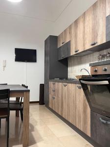 cocina con armarios de madera, mesa y TV en NicAnto's Home, en Bari