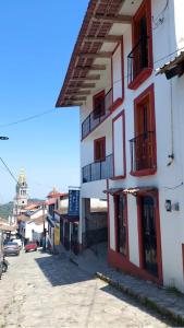 een gebouw met rode deuren en balkons in een straat bij Posada El Volador in Cuetzalán del Progreso