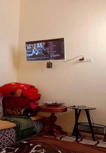 a living room with a table and a tv on the wall at Studio near the sea for surfing lovers welcome in Safi