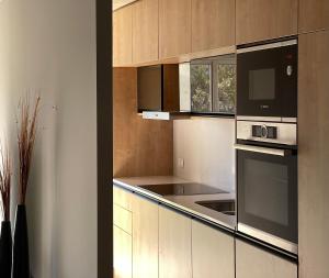 a kitchen with wooden cabinets and black appliances at Apartamento deluxe en Pocitos_Life Veintiseis Apartments in Montevideo