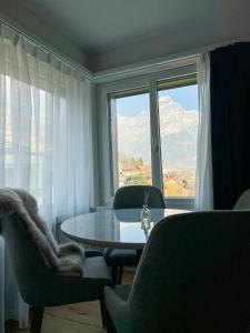 ein Wohnzimmer mit einem Tisch und Stühlen sowie einem großen Fenster in der Unterkunft Wunderstay Alpine 401 Chic Studio with Mountain view in Engelberg