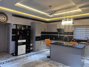 a kitchen with white cabinets and a island with orange chairs at T-Roys Apartments in Accra