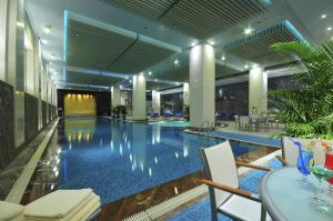 ein großer Pool in einem Hotel mit Stühlen und einem Tisch in der Unterkunft The Eton Hotel Shanghai in Shanghai