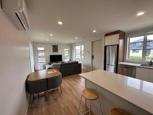 uma cozinha e sala de estar com uma mesa e um sofá em Cosy Self Contained 2 Bedroom Townhouse em Hamilton
