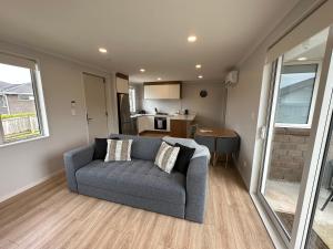 a living room with a couch and a kitchen at Cosy Self Contained 2 Bedroom Townhouse in Hamilton