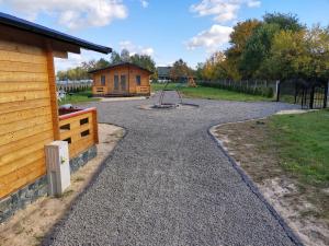 una entrada de grava con un parque infantil y una cabaña en LandsBy Apartments, en Ostrów Warcki
