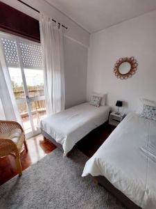 a white bedroom with two beds and a window at Charming Avenue Apartment in Faro