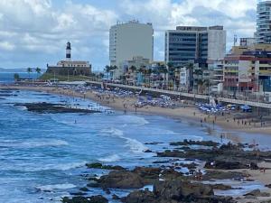 a beach with people and the ocean and buildings at Excelente localização na Barra -Climatizado-Garagem in Salvador