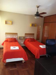 1 dormitorio con 2 camas con sábanas rojas y ventilador en Quinta House en Mendoza