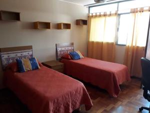 Habitación con 2 camas con sábanas rojas y ventana en Quinta House en Mendoza